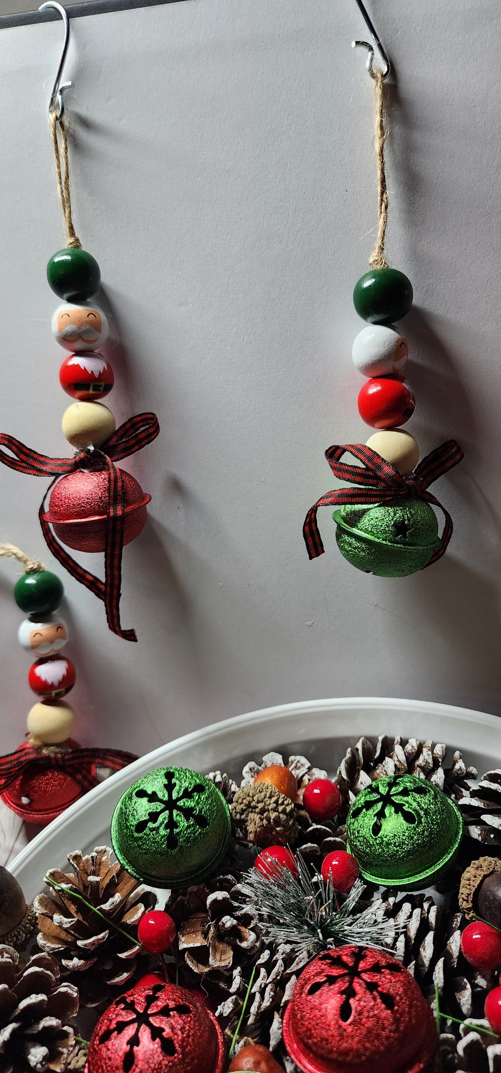 Wooden Christmas ornaments with Santa Claus beads and large green and red jingle bells. Buffalo plaid ribbon on bottom. Whimsical decor