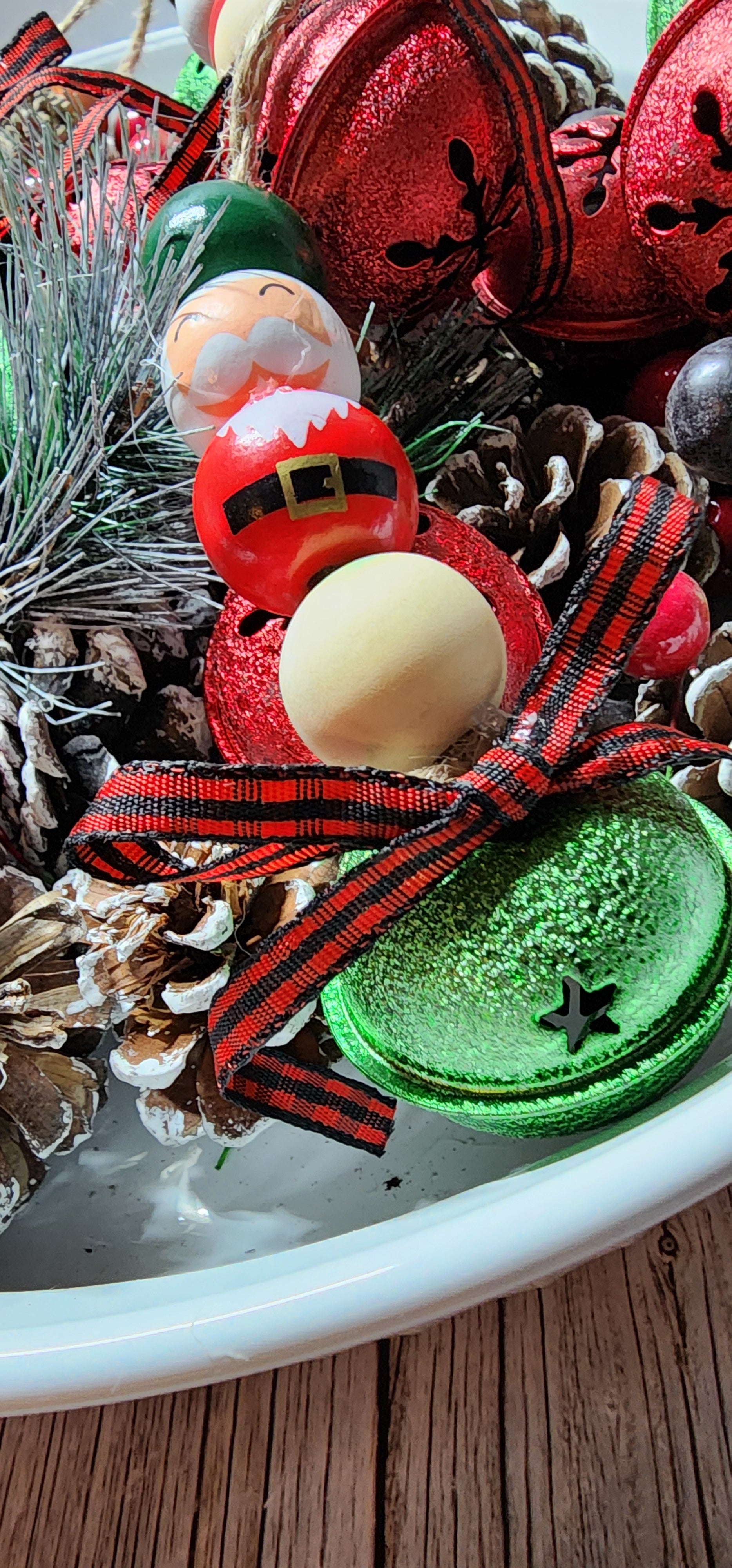 Wooden Christmas ornaments with Santa Claus beads and large green and red jingle bells. Buffalo plaid ribbon on bottom. Whimsical decor