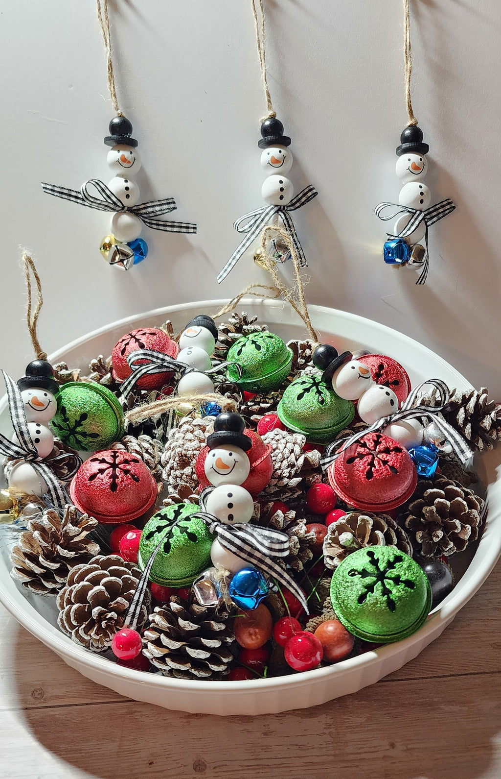Wooden Christmas ornaments with blue,  silver and gold jingle bells.  Snowman beads with black and white buffalo plaid bow. Festive decor