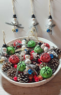 Wooden Christmas ornaments with blue,  silver and gold jingle bells.  Snowman beads with black and white buffalo plaid bow. Festive decor
