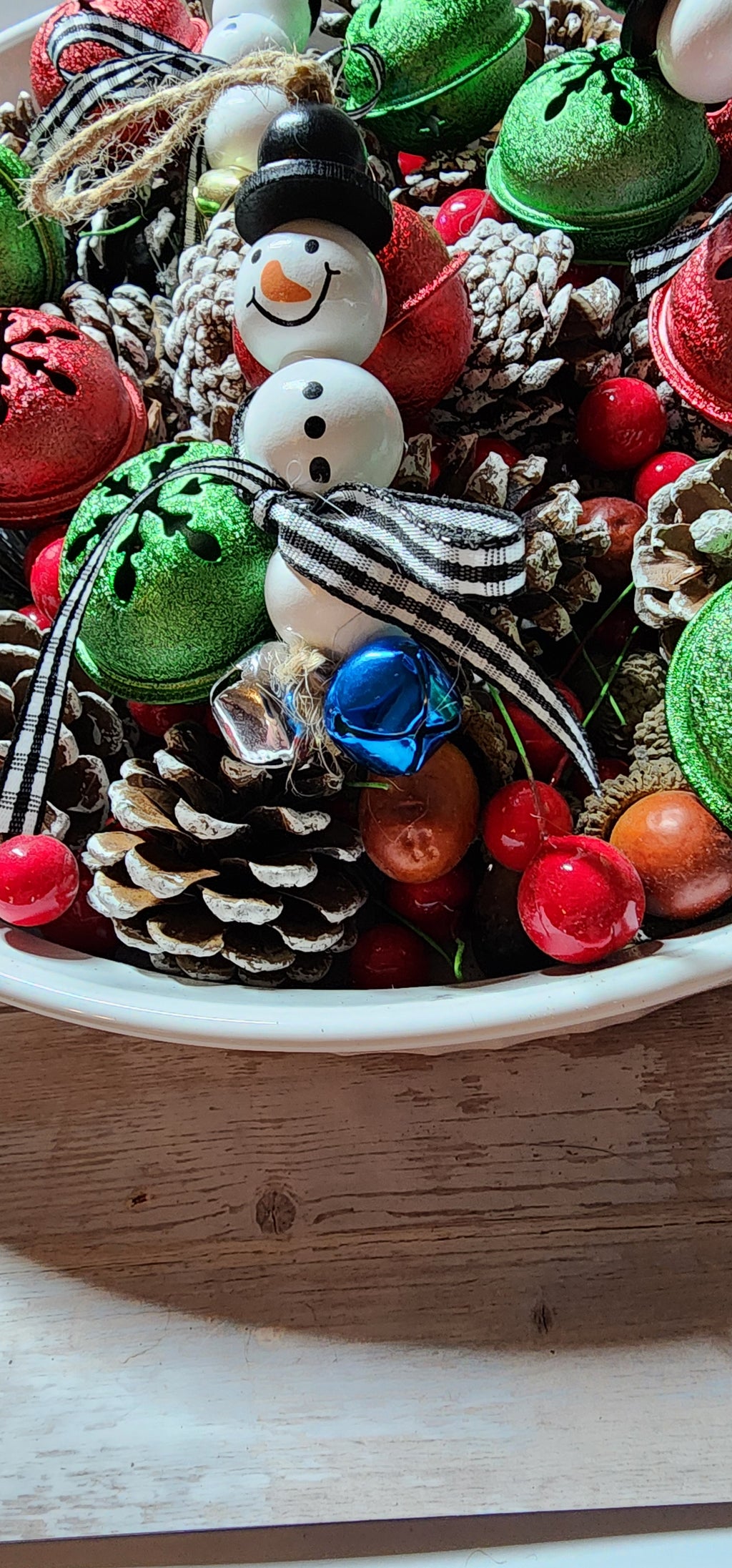 Wooden Christmas ornaments with blue,  silver and gold jingle bells.  Snowman beads with black and white buffalo plaid bow. Festive decor