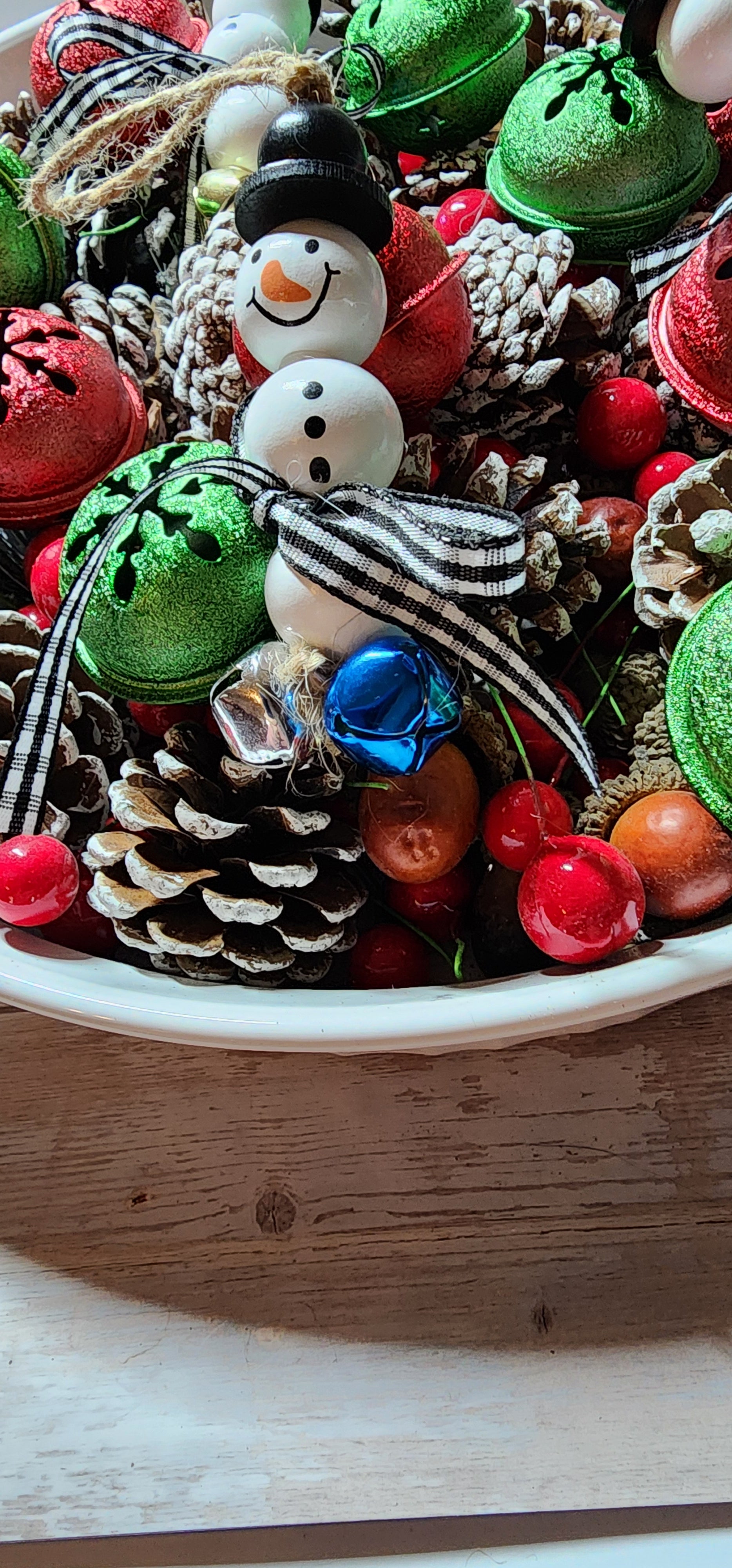 Wooden Christmas ornaments with blue,  silver and gold jingle bells.  Snowman beads with black and white buffalo plaid bow. Festive decor