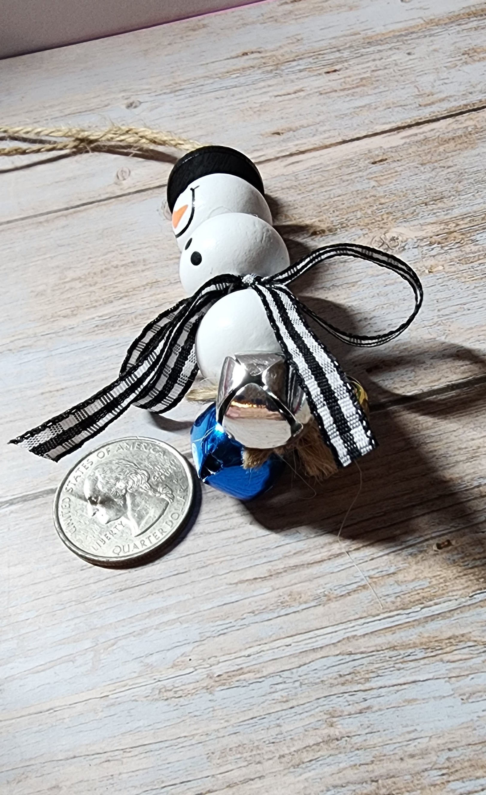 Wooden Christmas ornaments with blue,  silver and gold jingle bells.  Snowman beads with black and white buffalo plaid bow. Festive decor